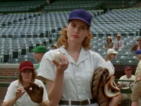 Still from A League of Their Own showing a woman with a baseball and glove looking at the camera
