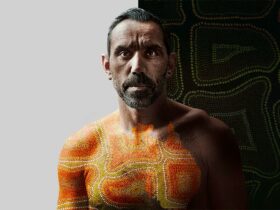 Promo still from The Australian Dream: a man with a dot painting of Australia overlaid on his chest