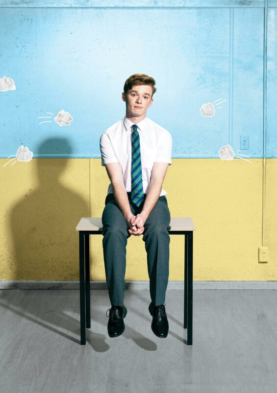School boy on desk with paper balls