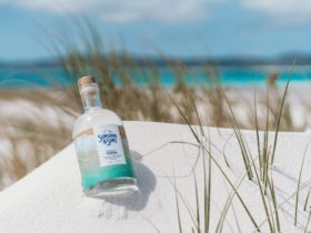 A bottle of our Original Vodka lying in white sand on the beach
