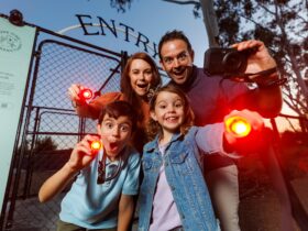 Young family with red-light torches at the entry gates to Nocturnal